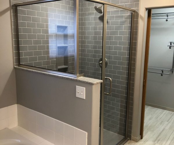 Standing shower with glass door and gray stone facade